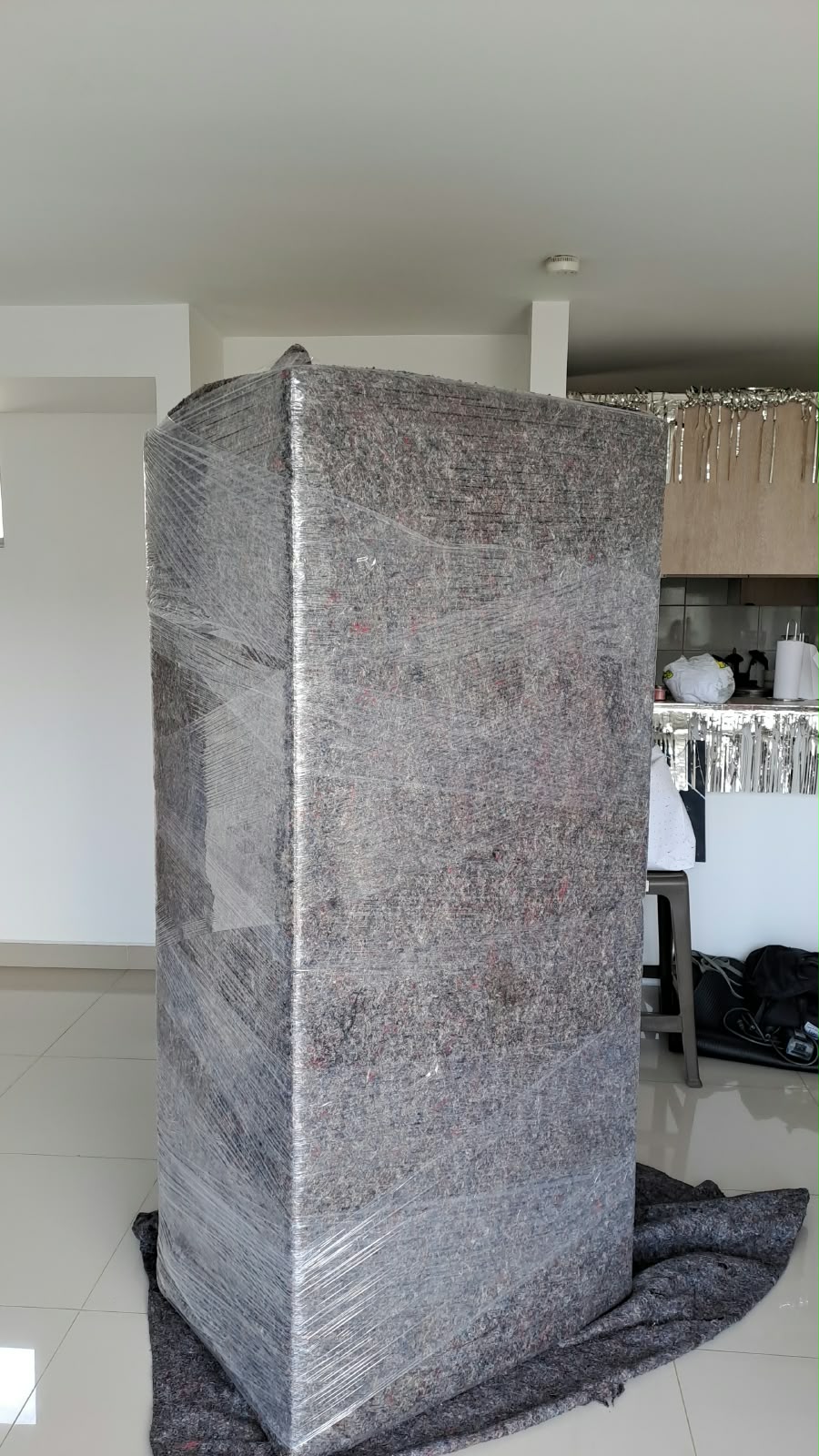 Electrodoméstico envuelto con manta protectora y película plástica.